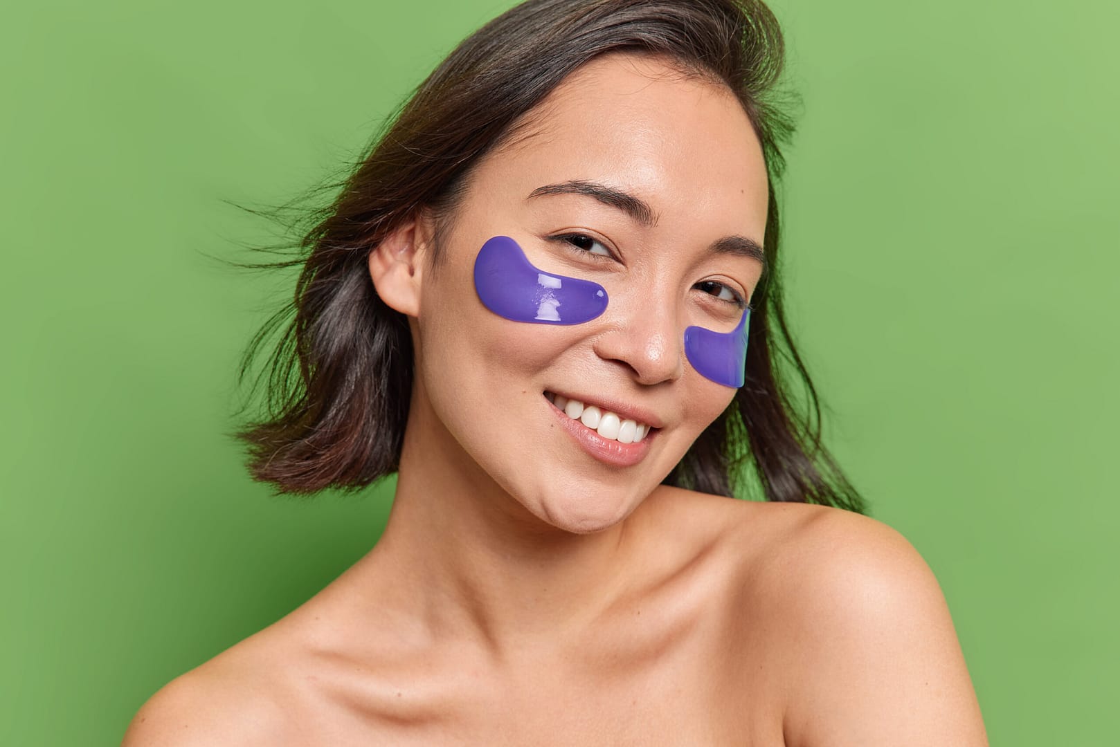 smiling woman applies blue hydrogel patches after cryotherapy floral park facial in new york