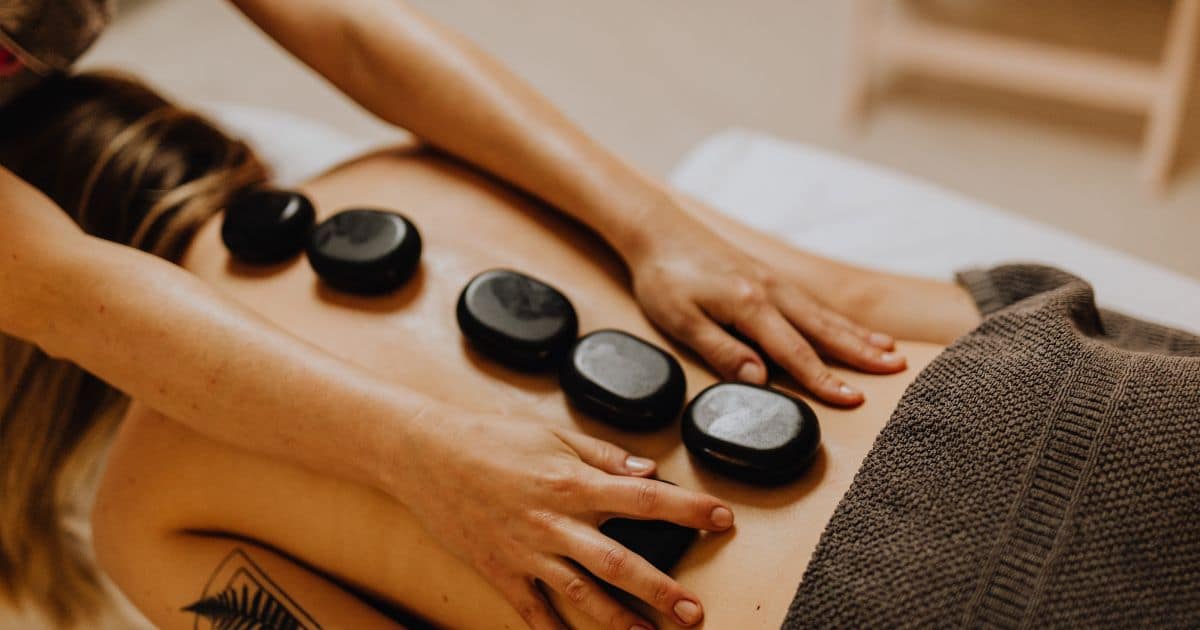 woman laying down with hotstones along her back