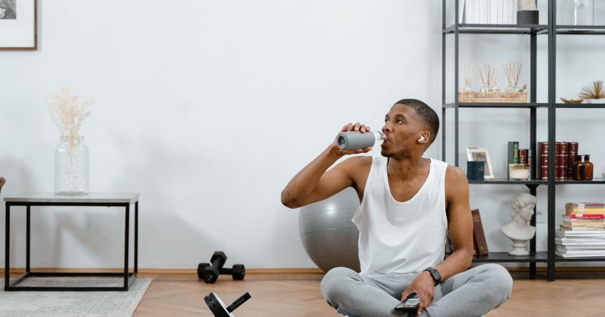 man sitting dring water from a canteen