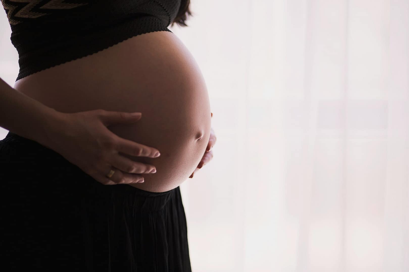 Expecting mother holds her pregnancy belly while at a prenatal and postpartum massage