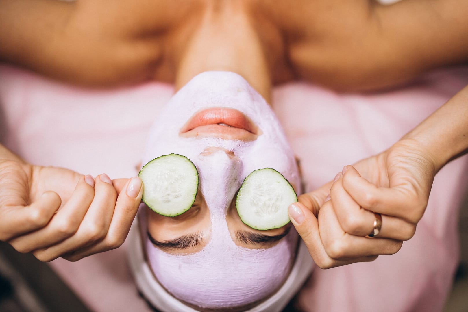 Woman with mask and cucmbers on her eyes at a spa for winter skin care treatment