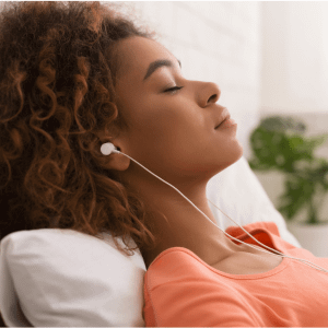 Woman laying on her back with ear buds and eyes closed