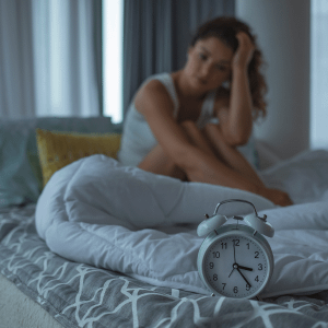 Woman sitting on bed with clock cant sleep
