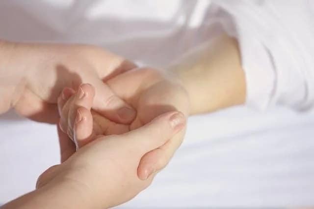A person massaging another person’s hand.