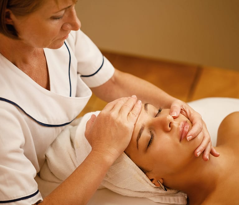 beautiful woman having head massage therapy and beauty treatment at a spa showing why healthcare workers massage therapy Is essential