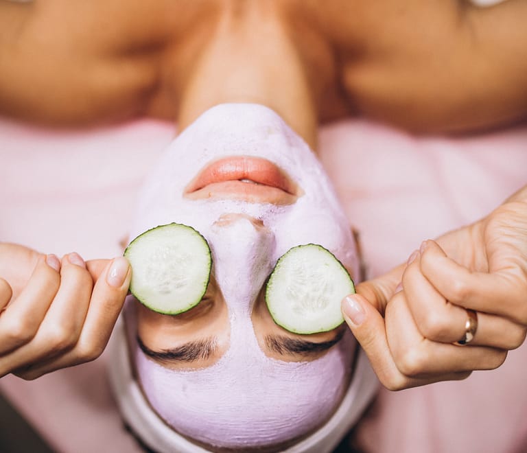 Woman with mask and cucmbers on her eyes at a spa for winter skin care treatment