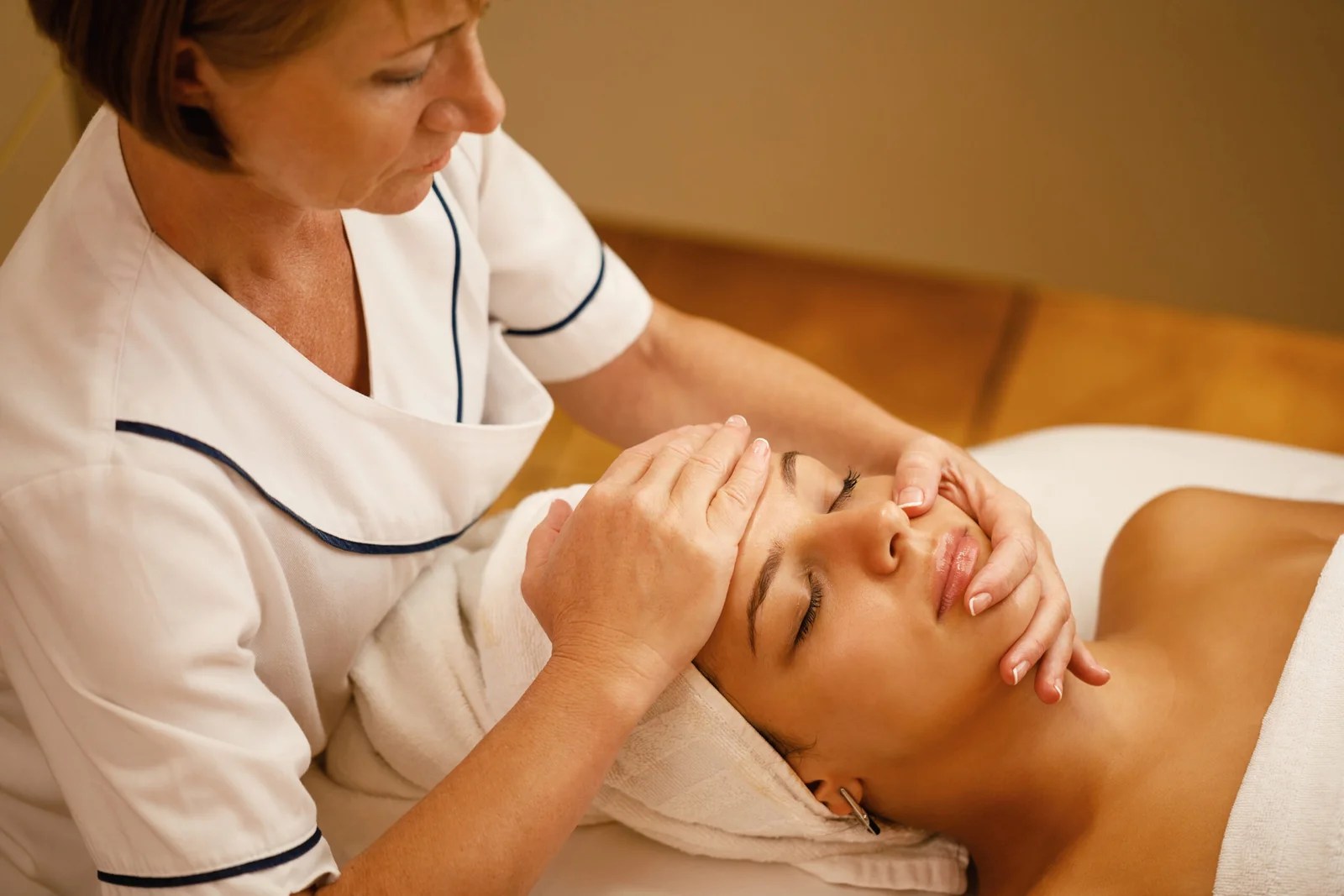 beautiful woman having head massage therapy and beauty treatment at a spa showing why healthcare workers massage therapy Is essential