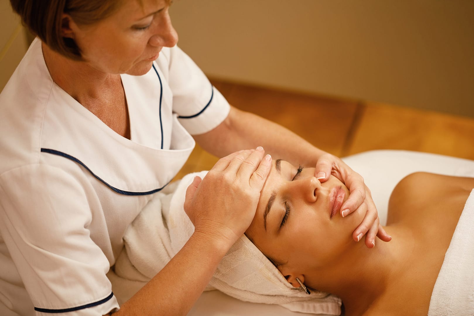beautiful woman having head massage therapy and beauty treatment at a spa showing why healthcare workers massage therapy Is essential