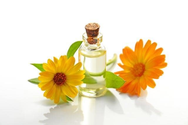 A small bottle with a cork next to two sunflowers.