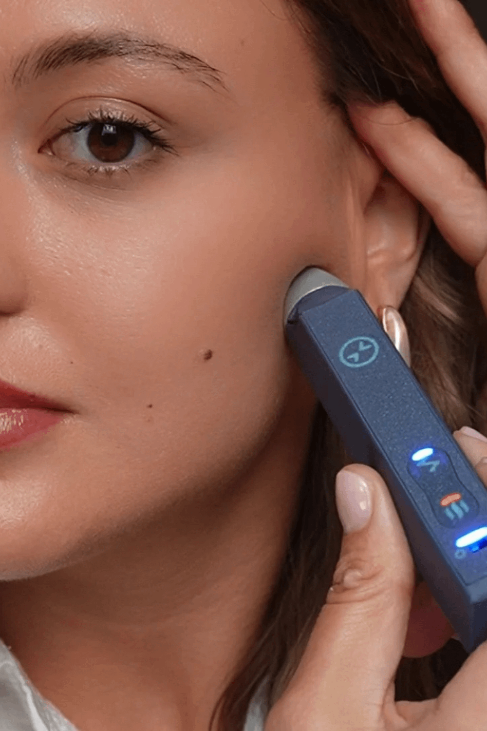 woman holding a tmj pen to the left side of her face