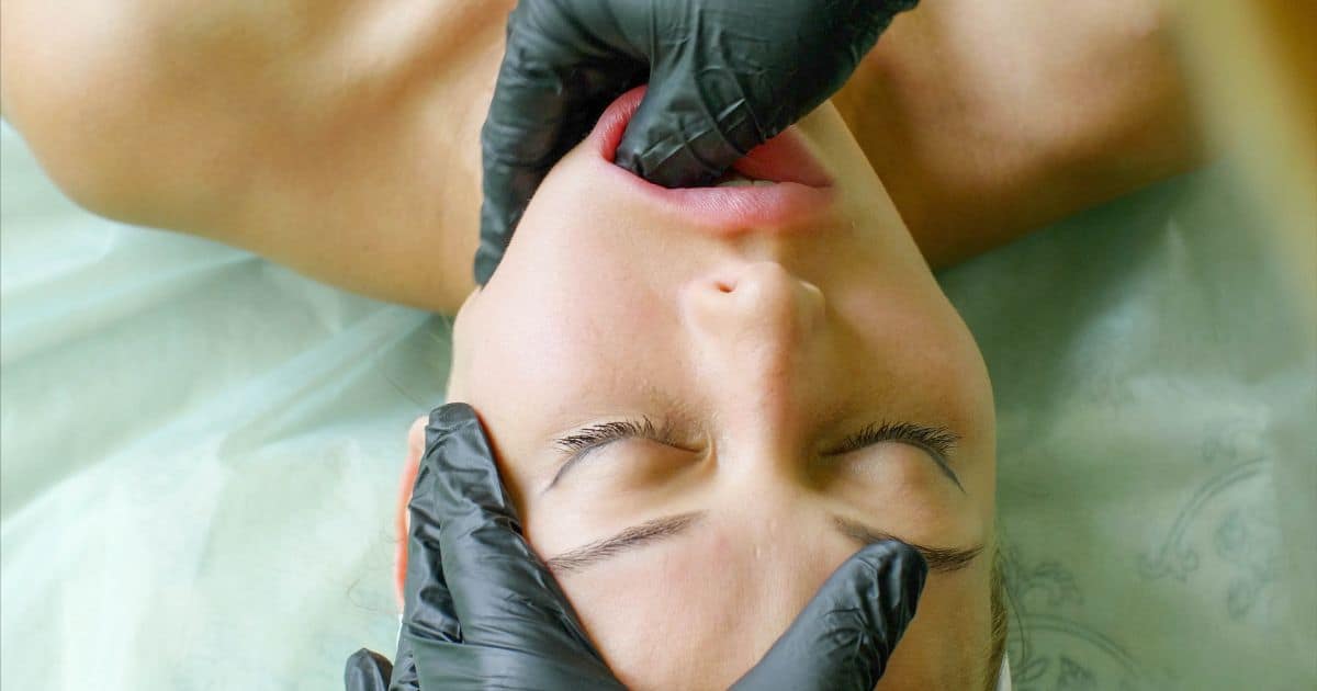 Woman laying on her back with therapist thumb massaging insider her mouth