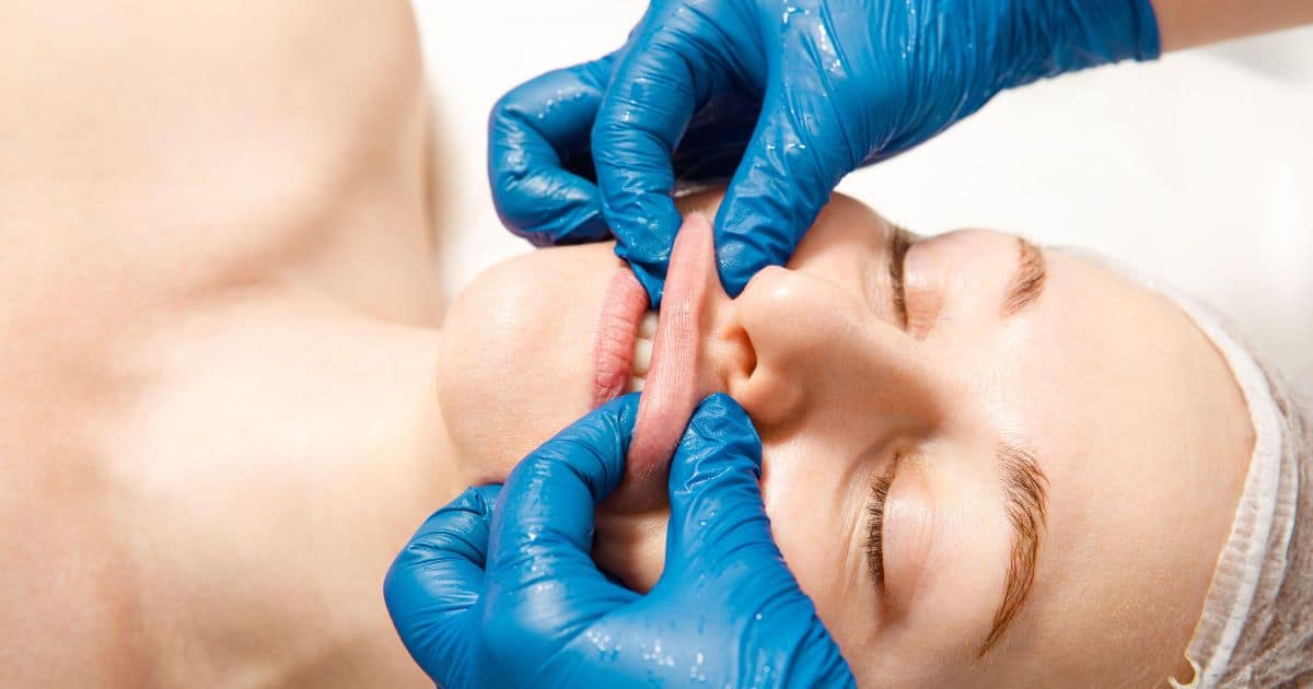 women laying down with therapist massaging her lips