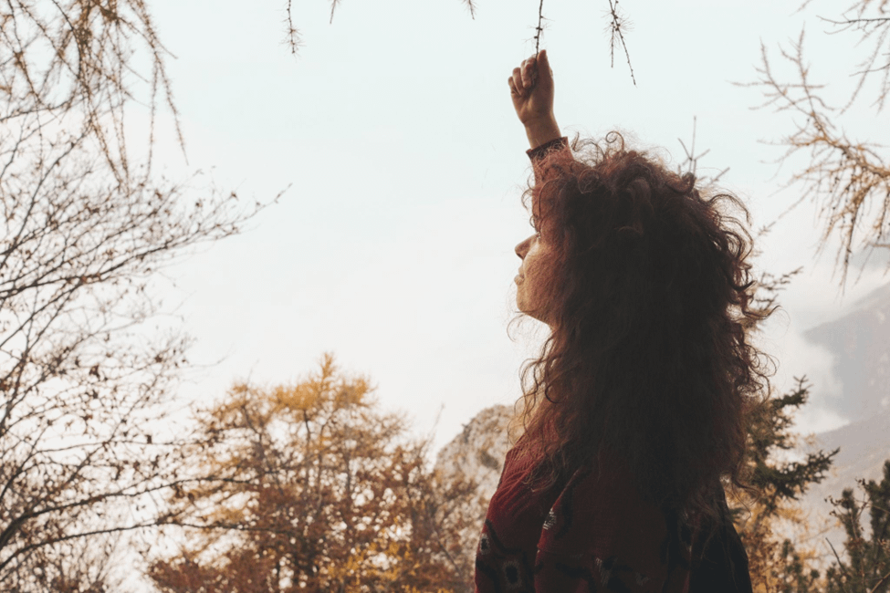 woman outside holding on to a tree branch
